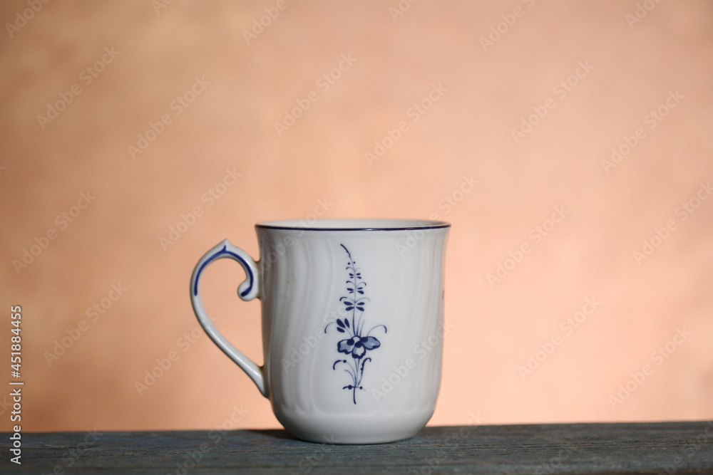 Fototapeta premium A white cup with a pattern stands on a wooden table