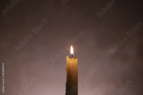 The candle is burning, on a dark background. Close-up