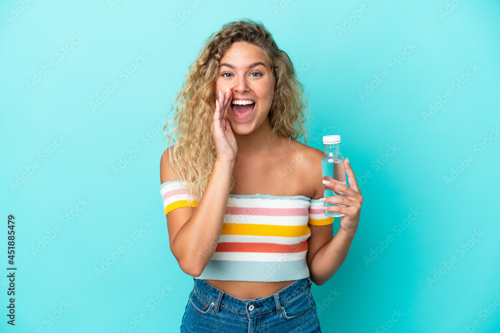 Young blonde woman with a bottle of water isolated on blue background shouting with mouth wide open Young blonde woman with a bottle of water isolated on blue background shouting with mouth wide open
