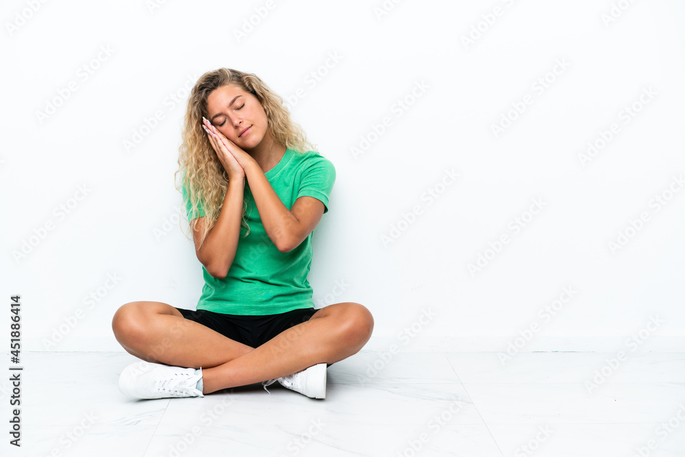 Girl with curly hair sitting on the floor making sleep gesture in dorable expression Girl with curly hair sitting on the floor making sleep gesture in dorable expression