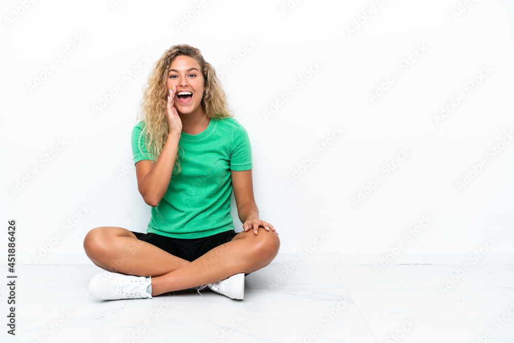 Girl with curly hair sitting on the floor shouting with mouth wide open Girl with curly hair sitting on the floor shouting with mouth wide open