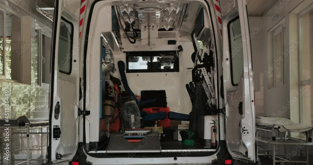 A wide-open ambulance stands in the middle of the hospital. An urgent matter. Life or death. The camera pans over the interior of the ambulance.