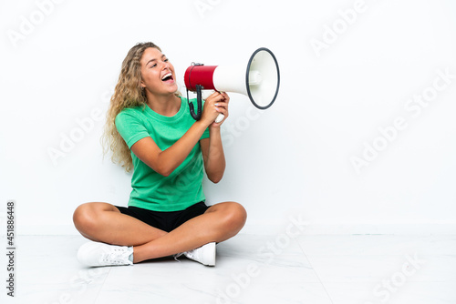 Girl with curly hair sitting on the floor shouting through a megaphone