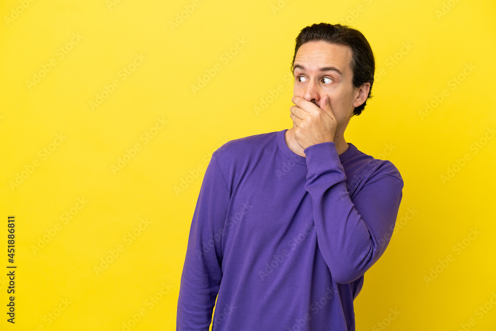 Young caucasian man isolated on yellow background doing surprise gesture while looking to the side Young caucasian man isolated on yellow background doing surprise gesture while looking to the side