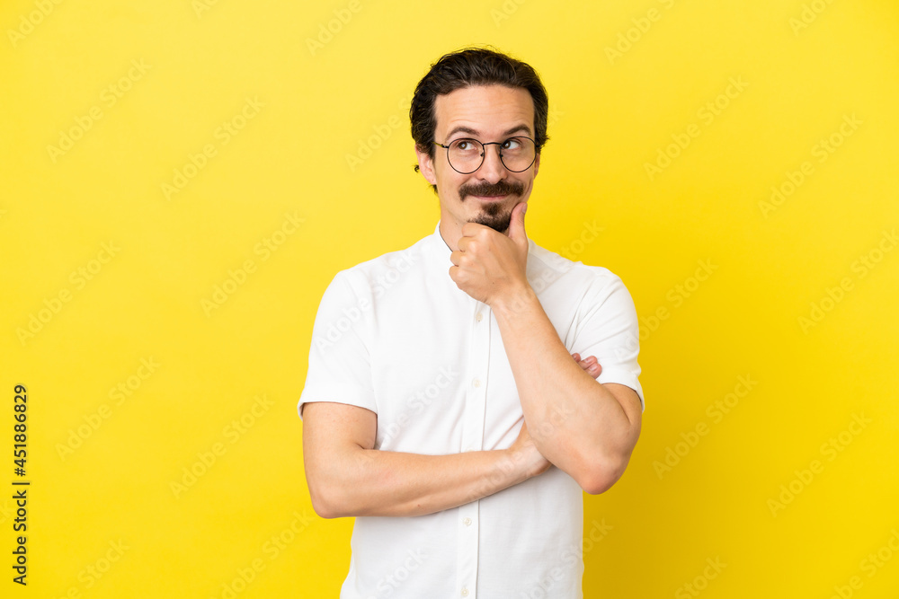 Young caucasian man isolated on yellow background thinking an idea while looking up Young caucasian man isolated on yellow background thinking an idea while looking up