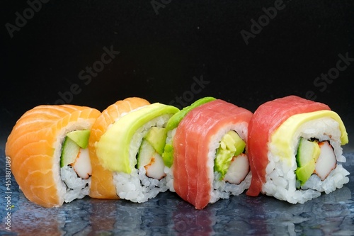 Mix different sushi with salmon, tuna, and surimi served on a grey plate with dark background