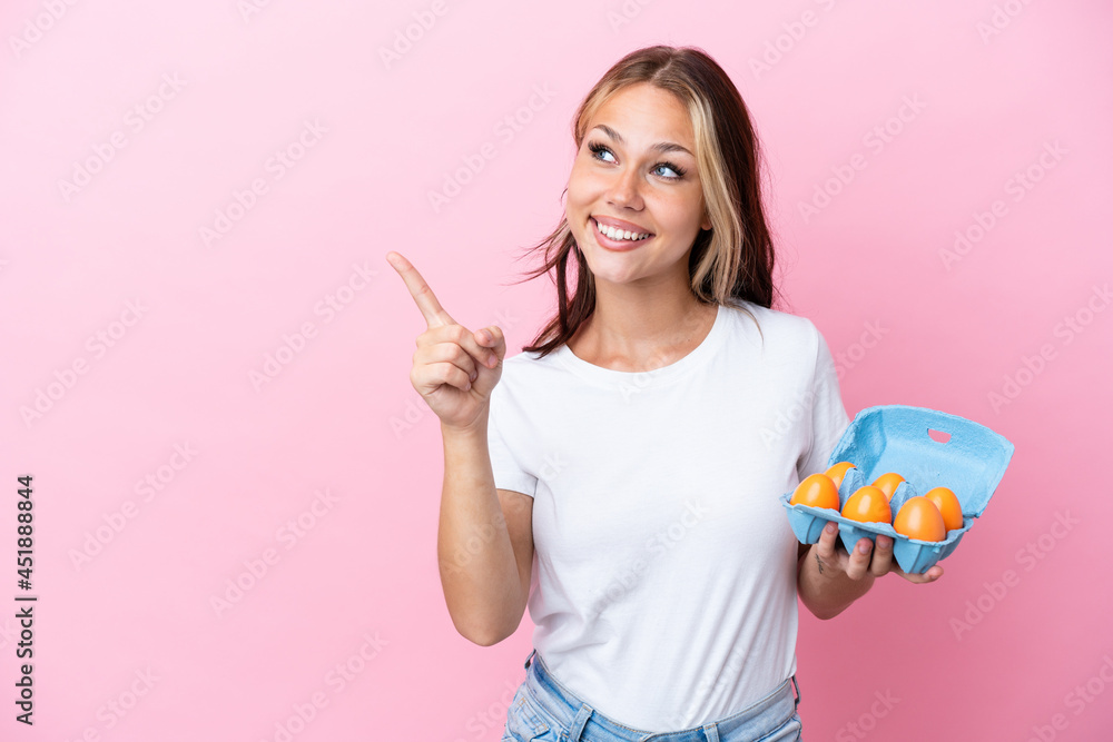 Young Russian woman holding eggs isolated on pink background intending to realizes the solution while lifting a finger up Young Russian woman holding eggs isolated on pink background intending to realizes the solution while lifting a finger up