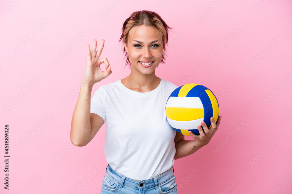 Young Russian woman playing volleyball isolated on pink background showing ok sign with fingers