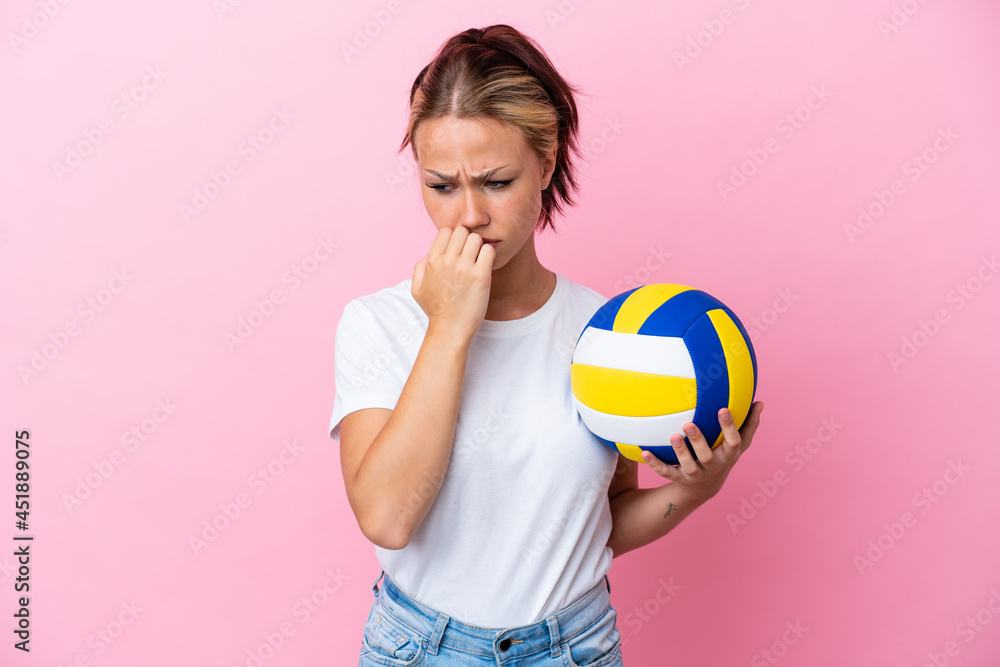 Young Russian woman playing volleyball isolated on pink background having doubts