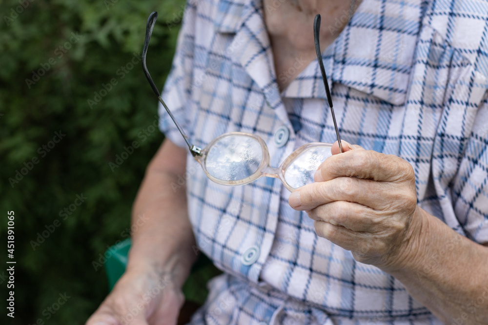 Fototapeta premium Senior woman holding glasses on her hand