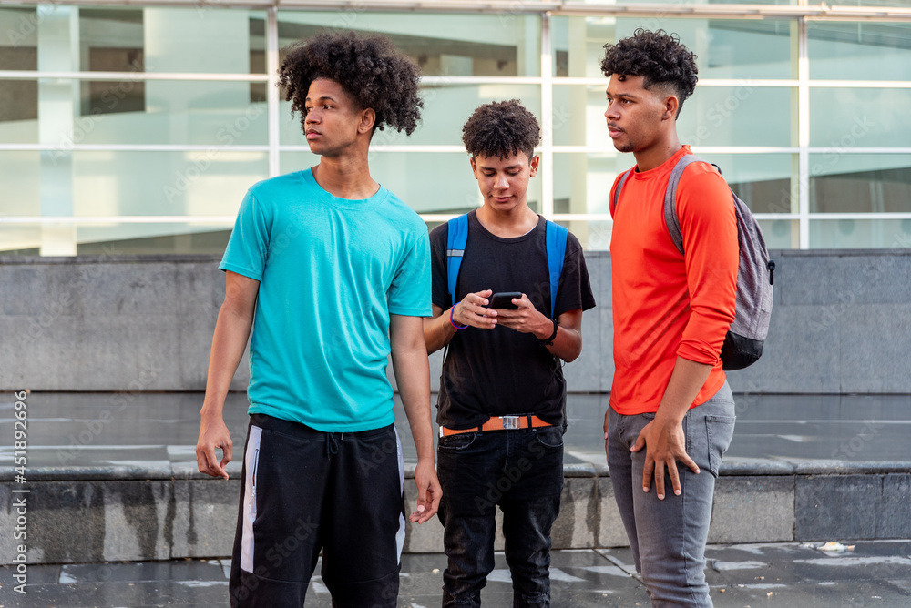 Multiethnic friends using mobile phone in the street Multiethnic friends using mobile phone in the street