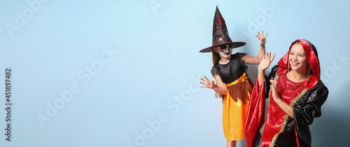Mother and little daughter in Halloween costumes on color background with space for text