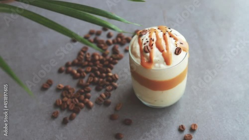 Ice coffee in the glass topped whipping cream with coffee beans. Cold summer drink.