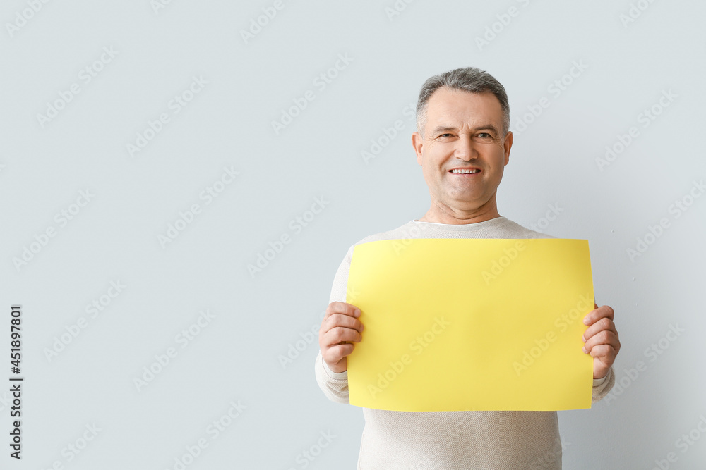 Mature man with blank poster on light background Mature man with blank poster on light background