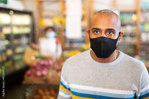 Portrait of Hispanic man in protective mask visiting grocery store during coronavirus pandemic..