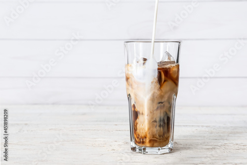 Pouring of milk into glass with tasty iced coffee on table photo