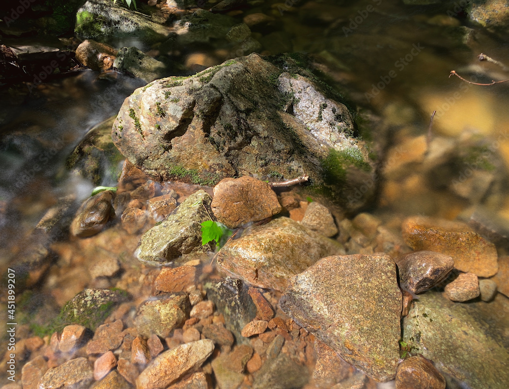 Stones in a stream. Long exposure of water flow. Close-up of rocks in a creek. Stones in a stream. Long exposure of water flow. Close-up of rocks in a creek.