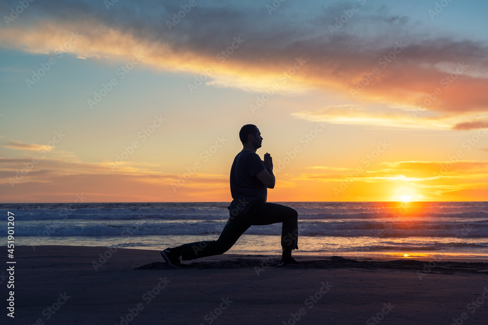 silhouette of a person on the beach doing yoga or exercise at beautiful sunset 