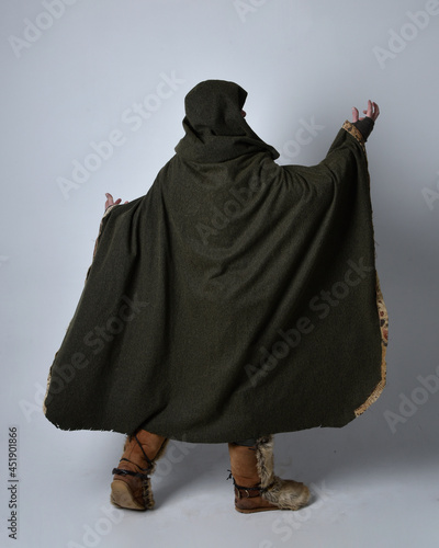 Full length  portrait of  young handsome man  wearing  medieval Celtic adventurer costume with hooded cloak facing away,  isolated on studio background. photo