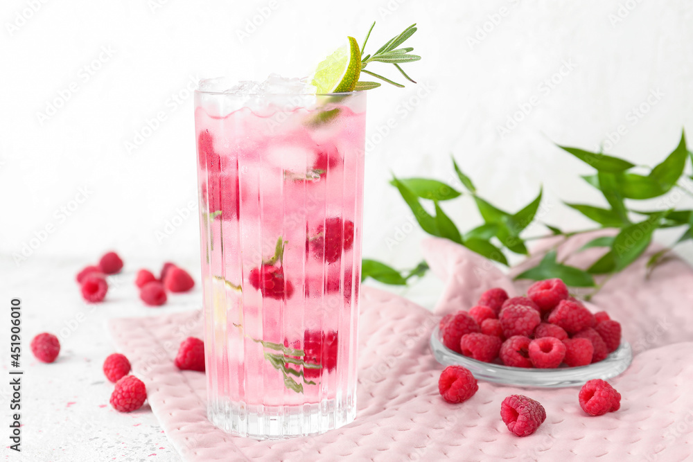 Glass of tasty raspberry lemonade and berries on light background Glass of tasty raspberry lemonade and berries on light background