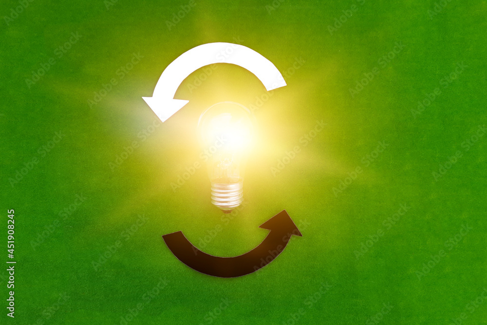 Electric light bulb, two round white and black arrows on a green background. The thought process, business ideas.