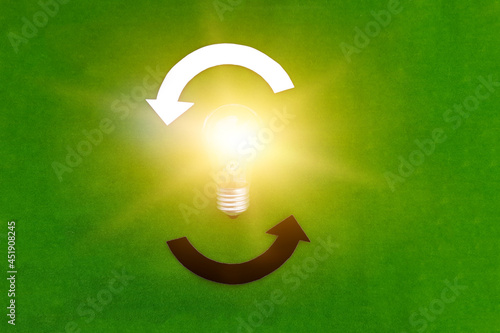 Electric light bulb, two round white and black arrows on a green background. The thought process, business ideas.