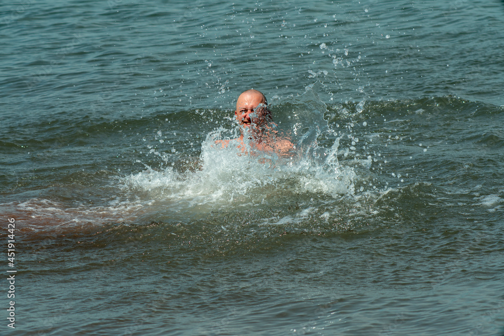 A man splashes merrily in the water of the sea.