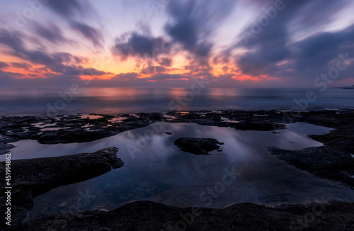 amazing scenic view at a sea shore from a coast after dramatic colorful sunset with flying blured clouds and reflection on water surface   beautiful ocean landscape