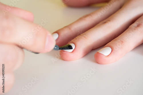 Close-up of applying white nail polish with a brush. Manicure at home. Poor-quality manicure