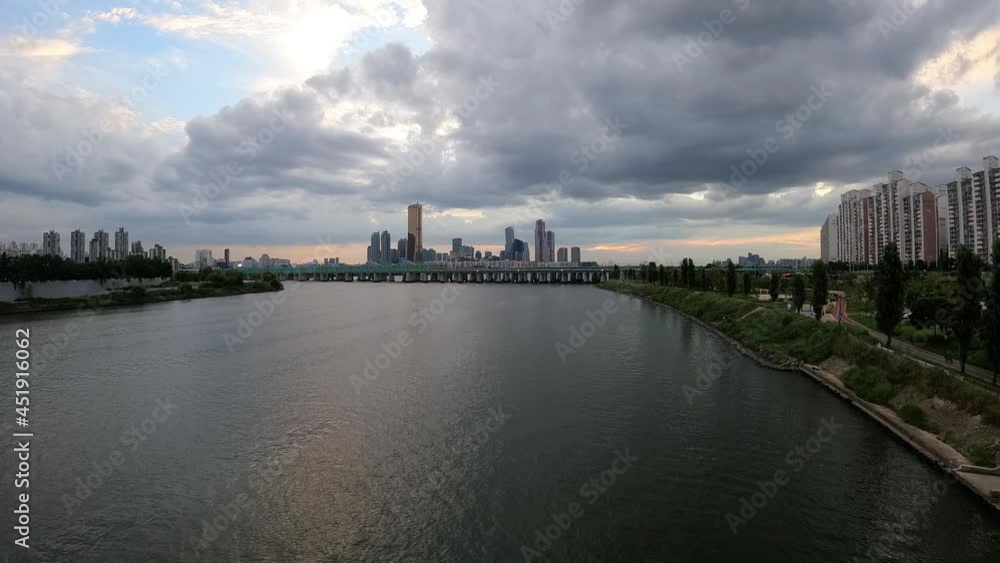 Cloudy Sky Over Han River In Seoul, South Korea With Railway Bridge And City Skyline In Distance. wide shot, time lapse Cloudy Sky Over Han River In Seoul, South Korea With Railway Bridge And City Skyline In Distance. wide shot, time lapse