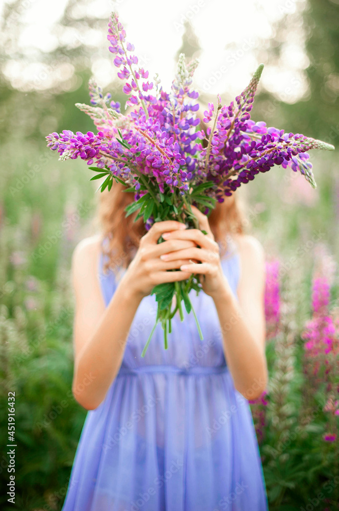 A girl holds a bouquet of lupines.