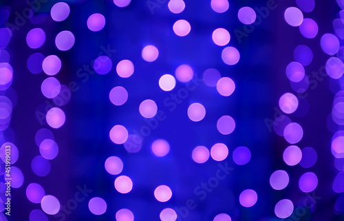 Abstract holiday bokeh background. Blurred lights of garland hanging on Christmas tree.