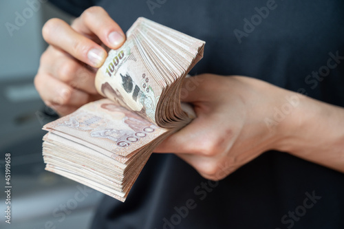 Fotografie Close up of someone hands counting a pile of one thousand Thai baht