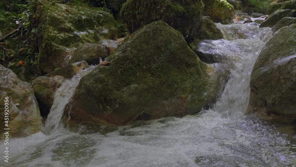 Close up slow motion of splashing little waterfall in wild nature of Switzerland - 4k Pan shot in green mountains with moss and trees in summer Close up slow motion of splashing little waterfall in wild nature of Switzerland - 4k Pan shot in green mountains with moss and trees in summer