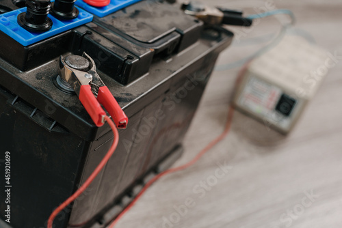 Closeup of car battery with copper clips attached to terminals