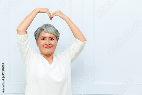 Senior asian woman making a love heart shape with her hands.