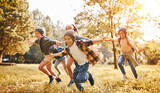 Group of happy joyful school kids boys and girls running with outstretched arms in forest on sunny day