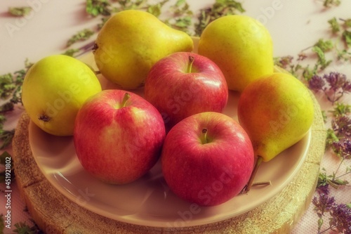 Four ripe pears and three red juicy apples are in the plate