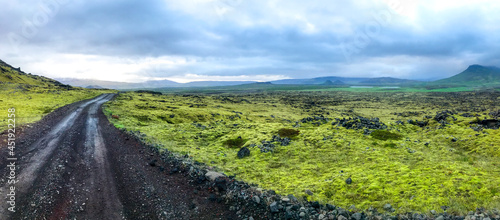 Road across lava Iceland rocks landscape and old volcano mount at horizon 