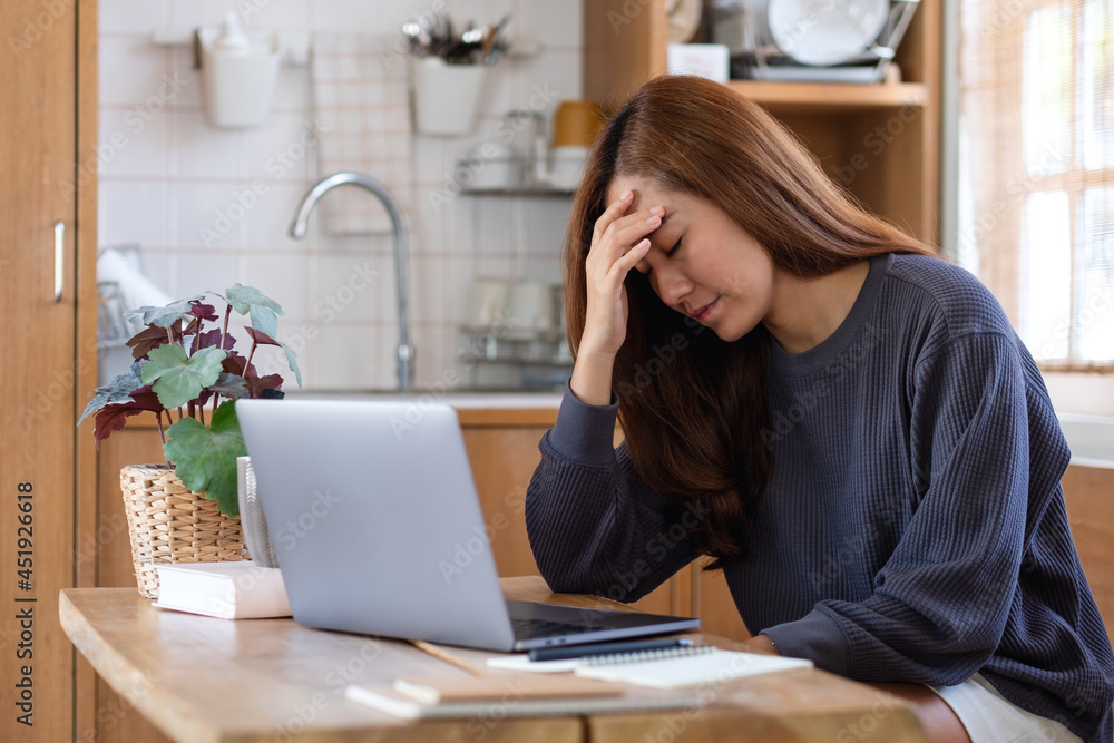 A young asian woman get sick and stressed while working or study online on laptop computer at home