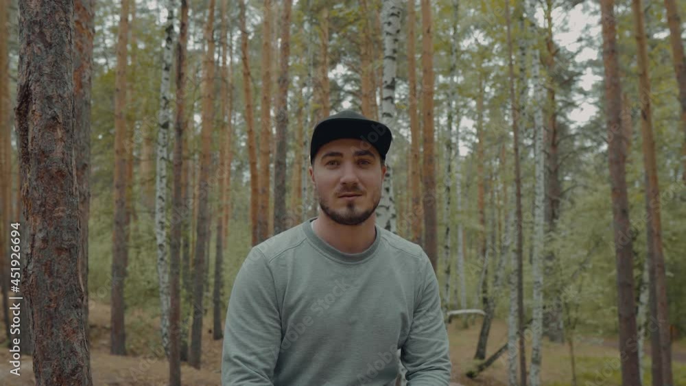 Portrait of an Attractive and Happy Male Traveler in the Forest. Portrait of Hicker in the Forest Among the Trees and Enjoys the Beauty of the Forest. Tourist. Hicker in the Woods at Rest Portrait of an Attractive and Happy Male Traveler in the Forest. Portrait of Hicker in the Forest Among the Trees and Enjoys the Beauty of the Forest. Tourist. Hicker in the Woods at Rest