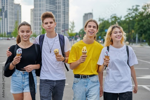 Group portrait of happy teenagers walking together with ice cream