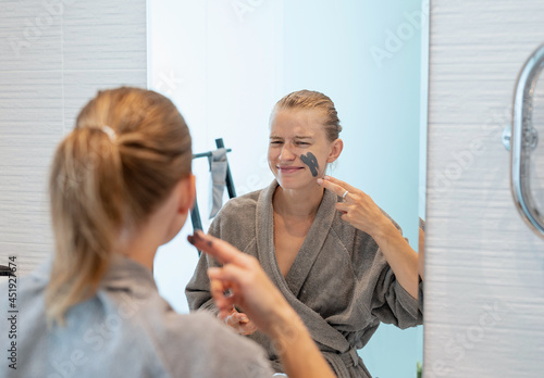Woman applying face mask in the bathroom