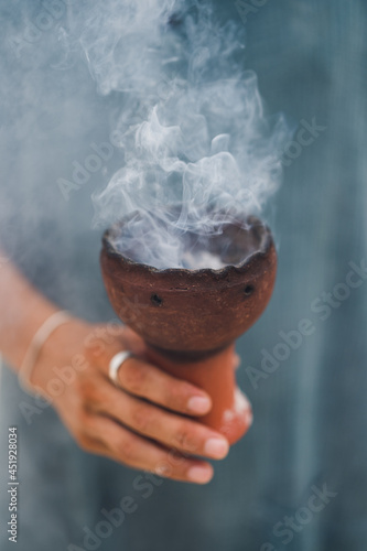 Foto copal encendido en una copalera sostenido por la mano de un hombre