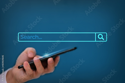 Businessman using smarthphone with searching browsing Internet Data Information with search bar on blue background, Search Engine Optimization SEO Networking Concept