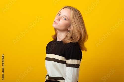 Cute blond teen girl. Studio image of smiling young girl on yellow background.