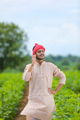 Indian farmer talking on smartphone at agriculture field.