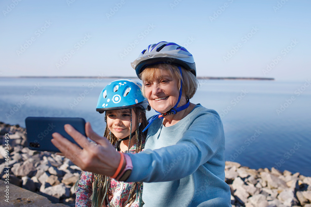 Happy senior woman taking selfie together with grandchild after riding on roller skates, hugs and support, family activity, spring or fall outdoors, healthy lifestyle Happy senior woman taking selfie together with grandchild after riding on roller skates, hugs and support, family activity, spring or fall outdoors, healthy lifestyle
