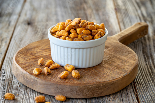 Roasted corn snack. Corn nuts with sauce on wood background. Bulk corn nut grains. Roasted corn nuts on a ceramic plate