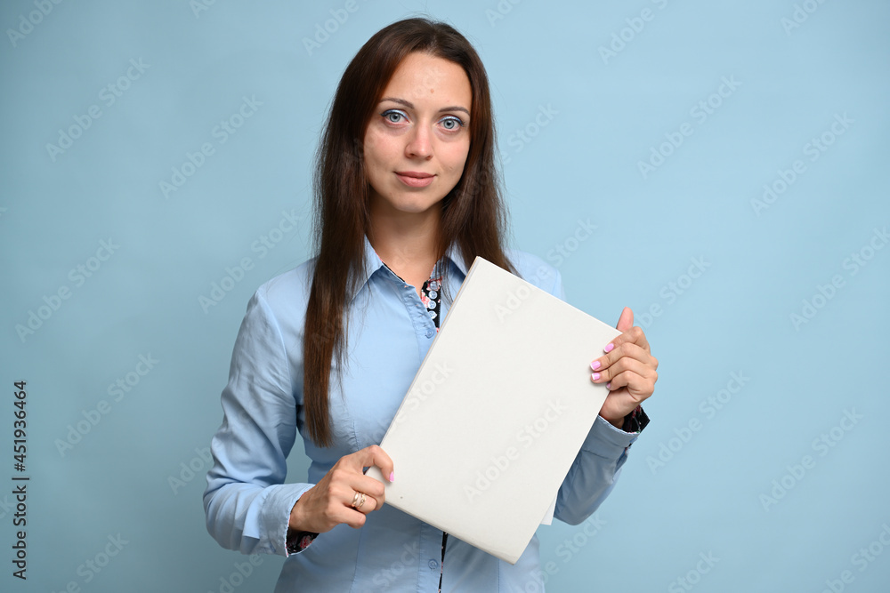 business woman with a smile in a blue shirt with a folder in her hands posing in the studio on a blue background business woman with a smile in a blue shirt with a folder in her hands posing in the studio on a blue background